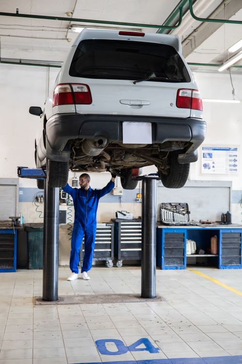 Mechanic working beneath a vehicle in a professional garage