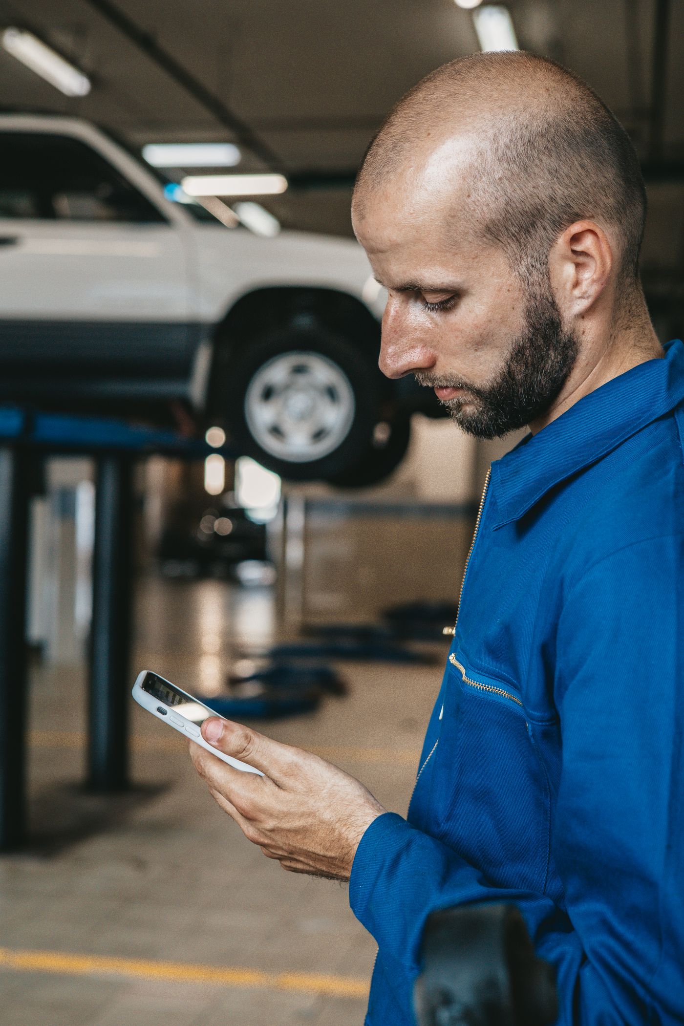 Mechanic checking a phone while working in a garage