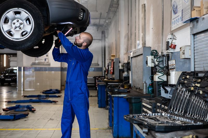 A professional mechanic inspects a car on a lift in a clean workshop.