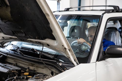 A Man in Blue Suit Checking a Car