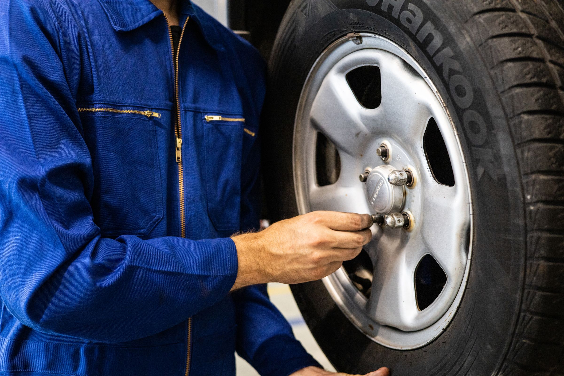 Mechanic tightening lug nuts on a mounted vehicle wheel to the correct torque specification