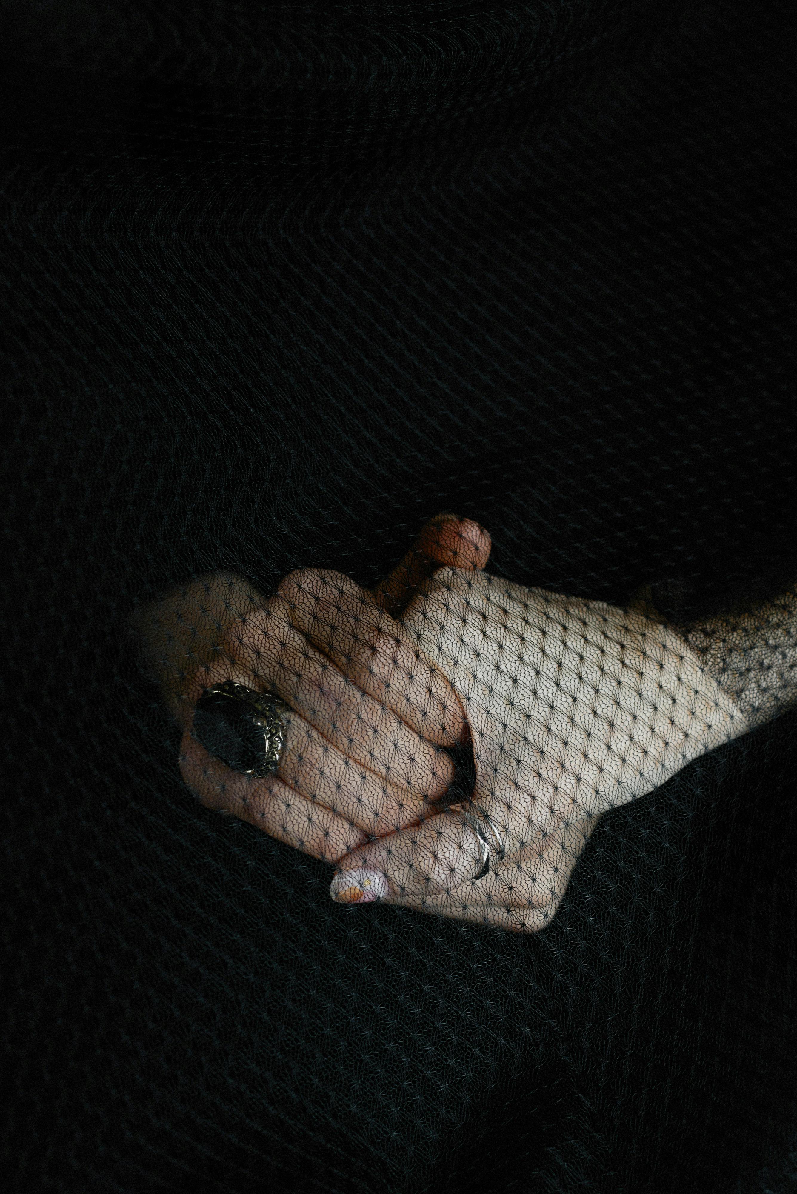 A portrait of hands clasped under a black veil, symbolizing elegance and mourning.