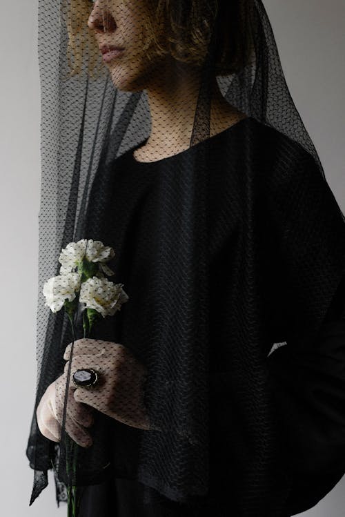 Widow Holding Flowers Behind Her Veil