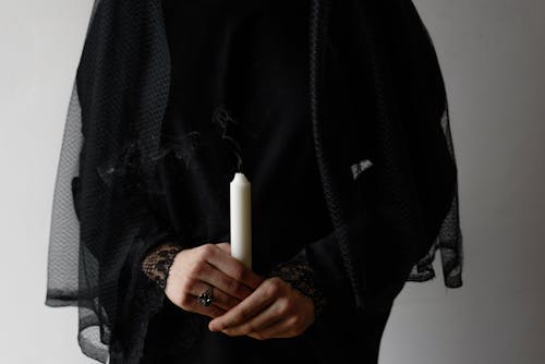 Person in Black Long Sleeve and Black Veil Holding White Candle