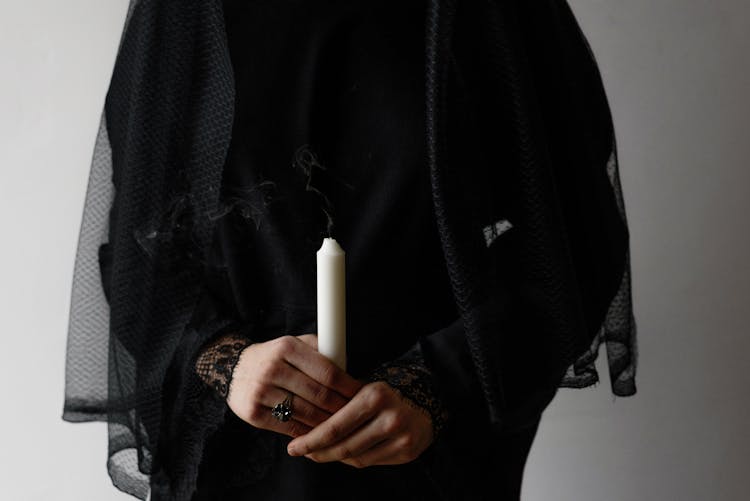 Person In Black Long Sleeve And Black Veil Holding White Candle