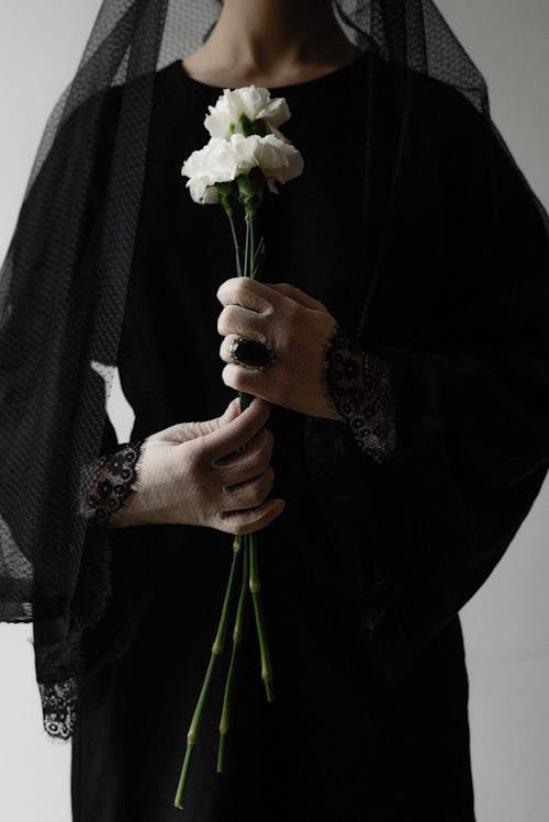 Person in Black Clothes Holding White Flowers
