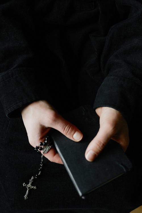 Free A Person Holding a Book and a Rosary Stock Photo