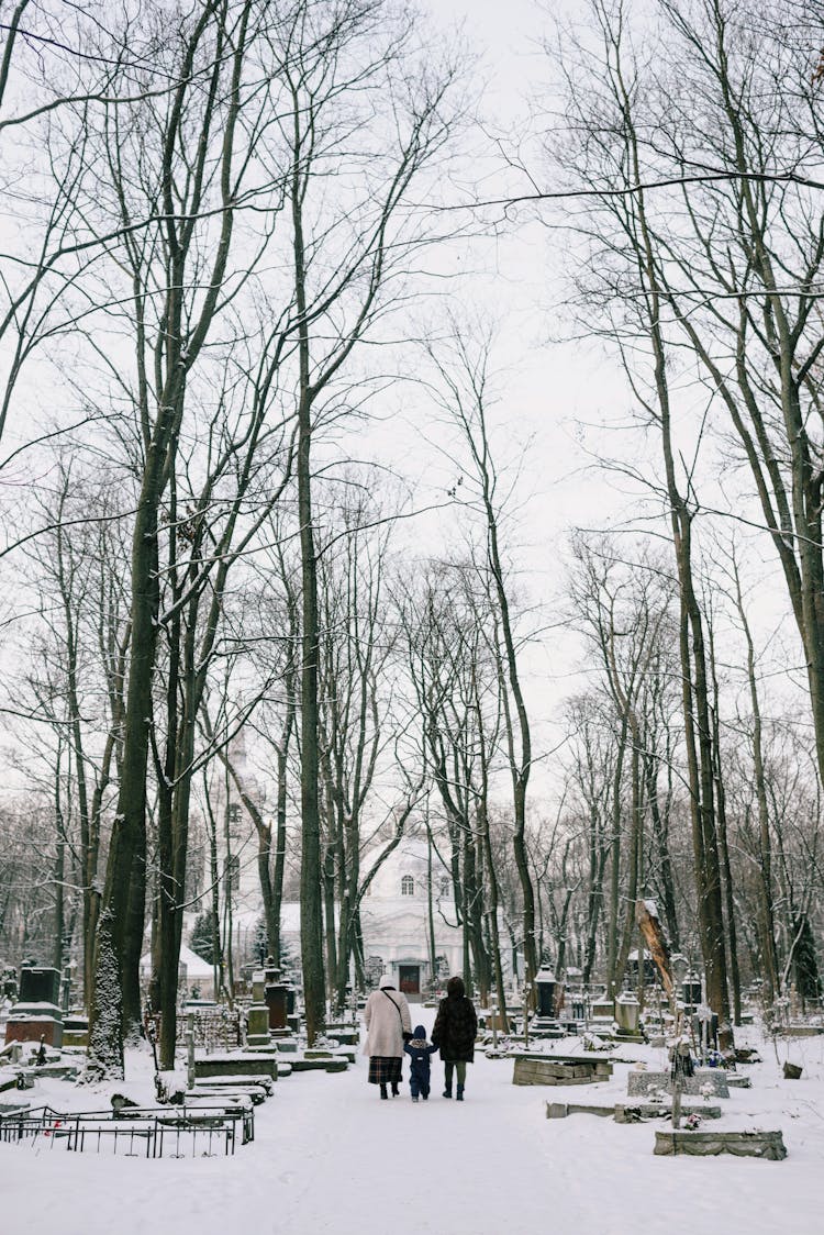 People Walking Together On A Snowy Cemetery