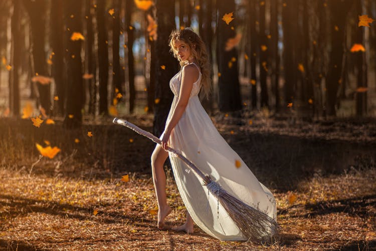 A White Witch Holding A Broomstick