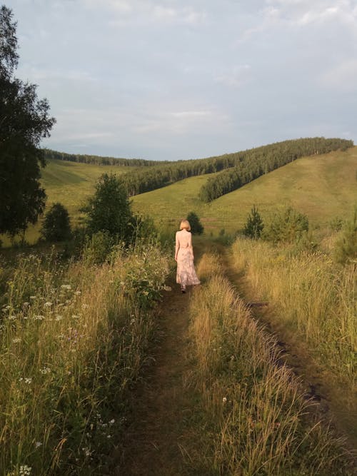 Back View of a Woman Walking in a Grass Field