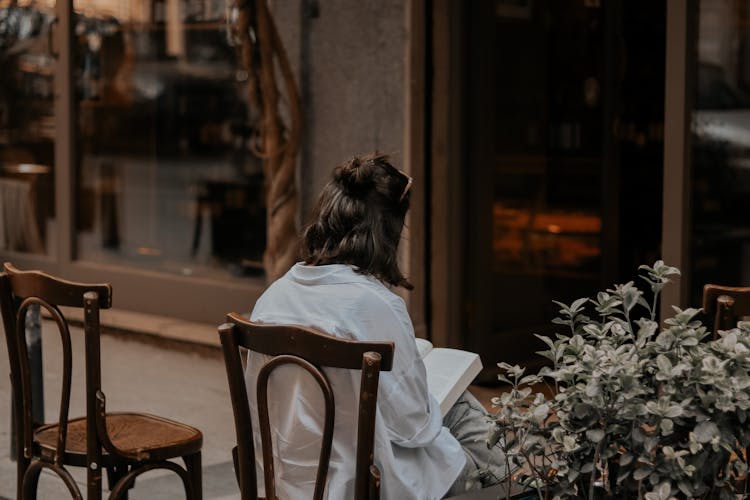 Backside Of A Seated Woman Reading A Book