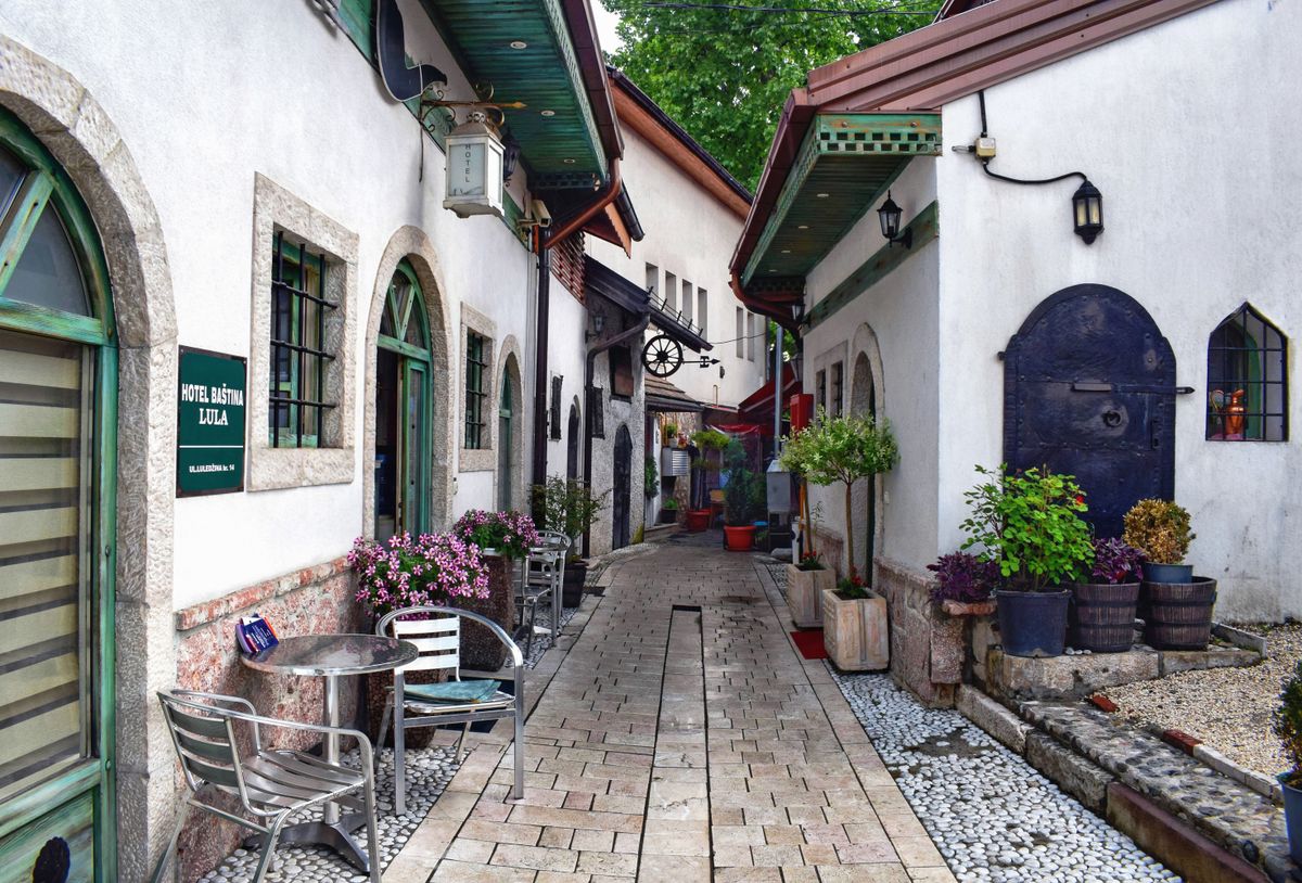 Ulicioară din orașul vechi al Sarajevoului, cu o cafenea și ghivece cu flori