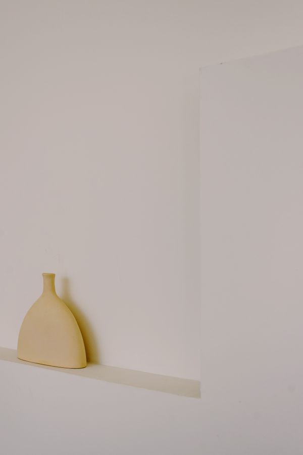 Beige vase on a white shelf — photo by Ksenia Chernaya on Pexels