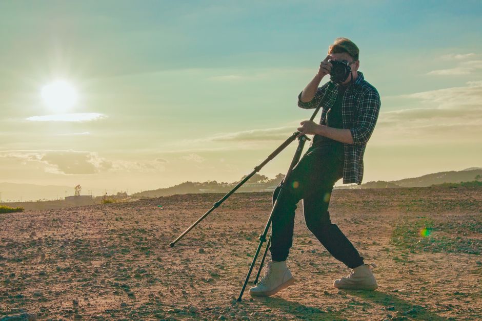photographer using a tripod for landscape photography at sunset - best photography gear