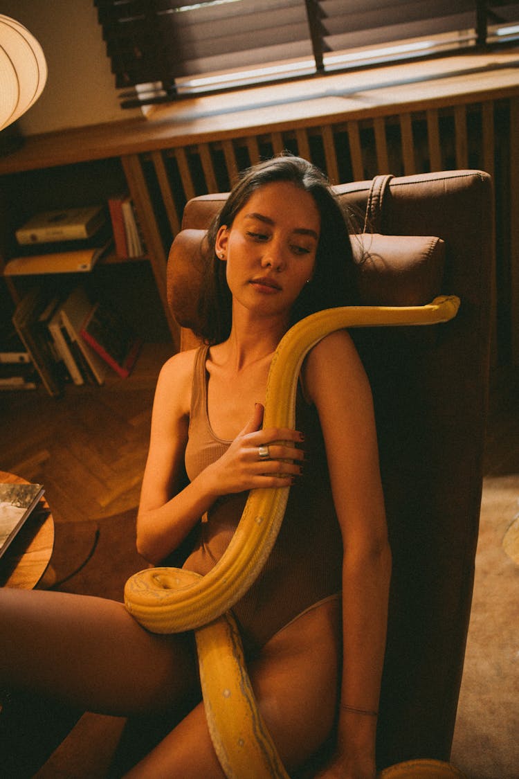 A Woman Sitting On A Chair Holding A Pet Snake