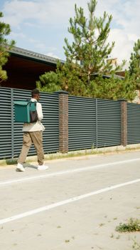 A delivery man walks down a city street with a green backpack, showcasing urban logistics.