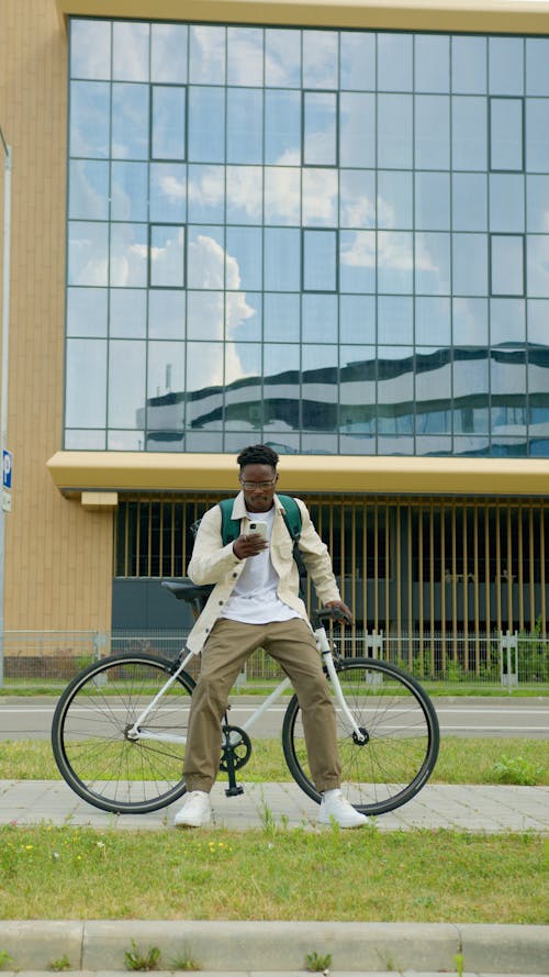 A Man Sitting on a Bicycle Using a Smartphone