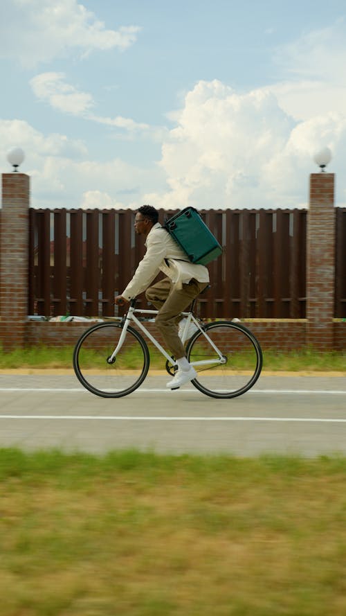 Photo of a Deliveryman Riding a Bicycle, against a Fence