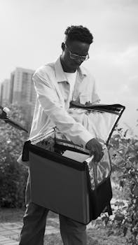 Monochrome image of a delivery person opening a thermal bag, taken outdoors.