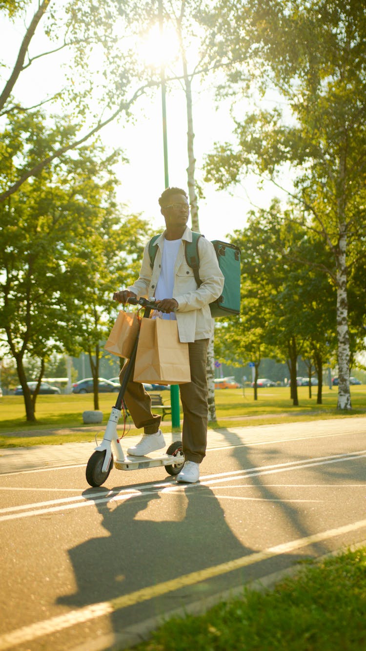 A Delivery Person On An E Scooter At A Park