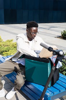 Delivery man arranging packages on a bench outdoors. Efficient urban delivery service in action.