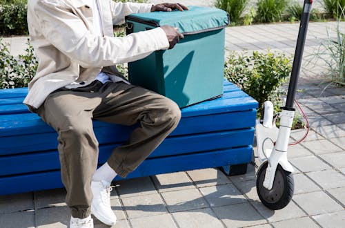A Man Sitting on a Bench While Holding a Thermal Bag