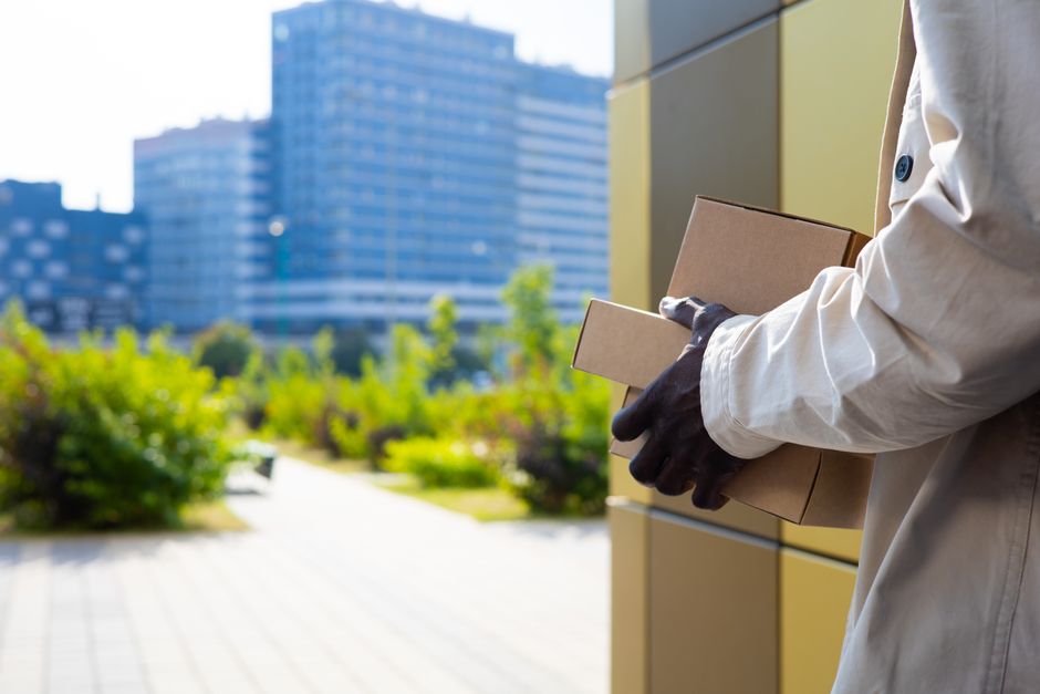 現代的な建物がある都市環境で荷物を運ぶ配達員。