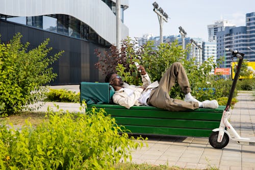 A Man Lying on a Wooden Bench while using a Smartphone