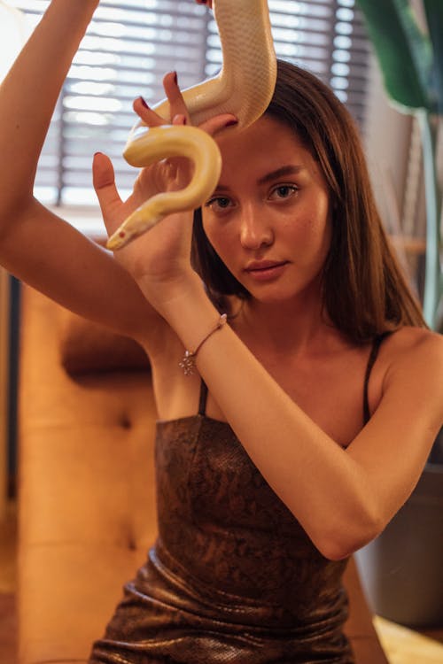 Woman in Brown Spaghetti Strap Top Holding a Snake