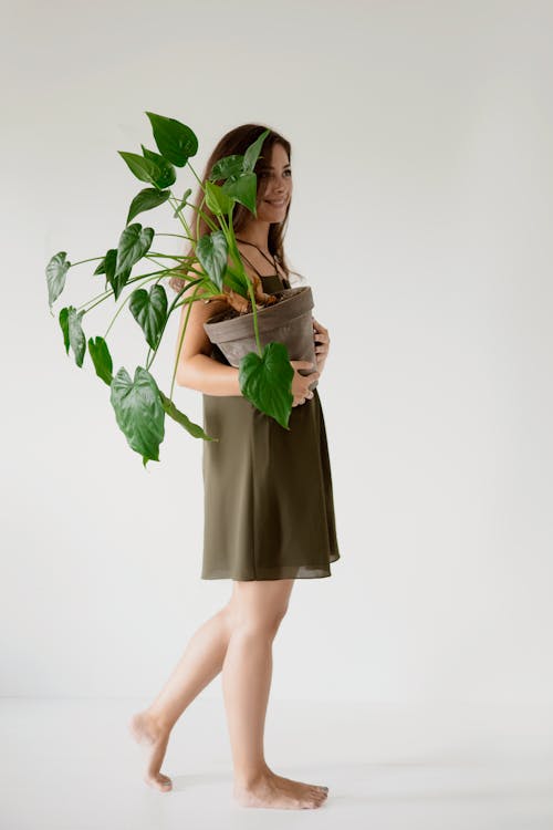 A Woman Holding a Potted Plant with Green Leaves
