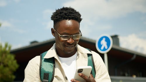Close-Up Shot of a Man Smiling while Looking at His Cellphone