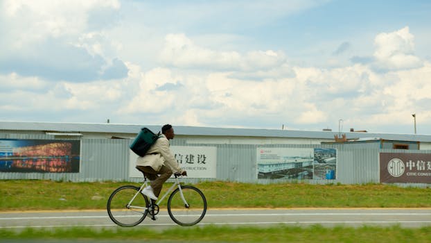 A delivery cyclist rides quickly along an urban road, carrying a large backpack.
