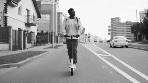 Free Monochrome image of a man riding an electric scooter down a city street. Stock Photo