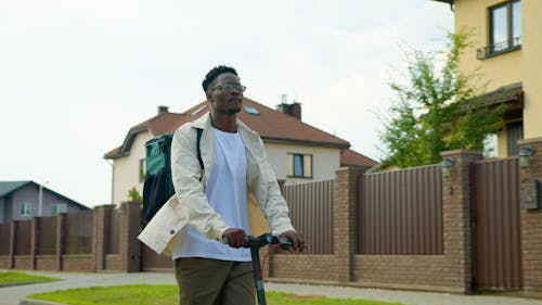 A Man with Backpack Riding a Scooter