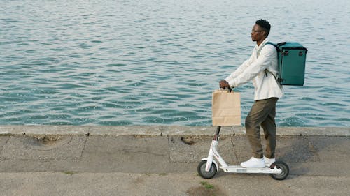 A Man in a White Long Sleeves Riding a Scooter Near the Sea