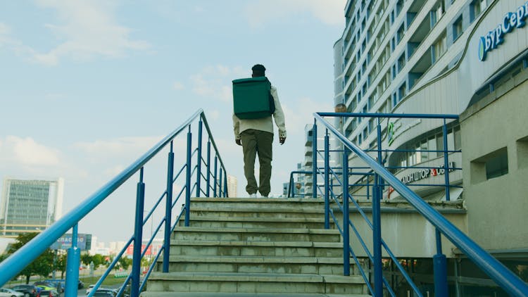 Man Carrying A Delivery Bag Walking Up The Stairs