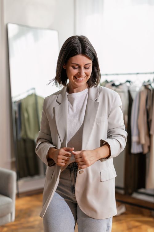 Free Fashionable woman smiling in a modern gray blazer indoors, showcasing style. Stock Photo