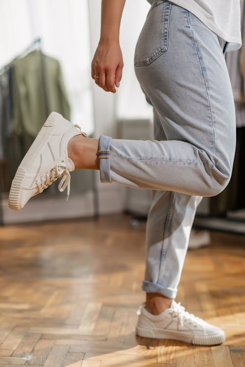 A Person Wearing Denim Pants and White Sneakers