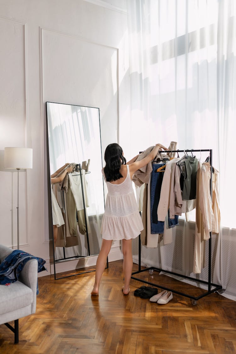 Woman In White Dress Putting Clothes On A Clothing Rack