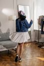 Woman in Blue Jacket and White Skirt Standing Beside White Sofa