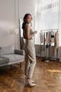 Woman in White Tank Top and White Pants Standing Beside Bed