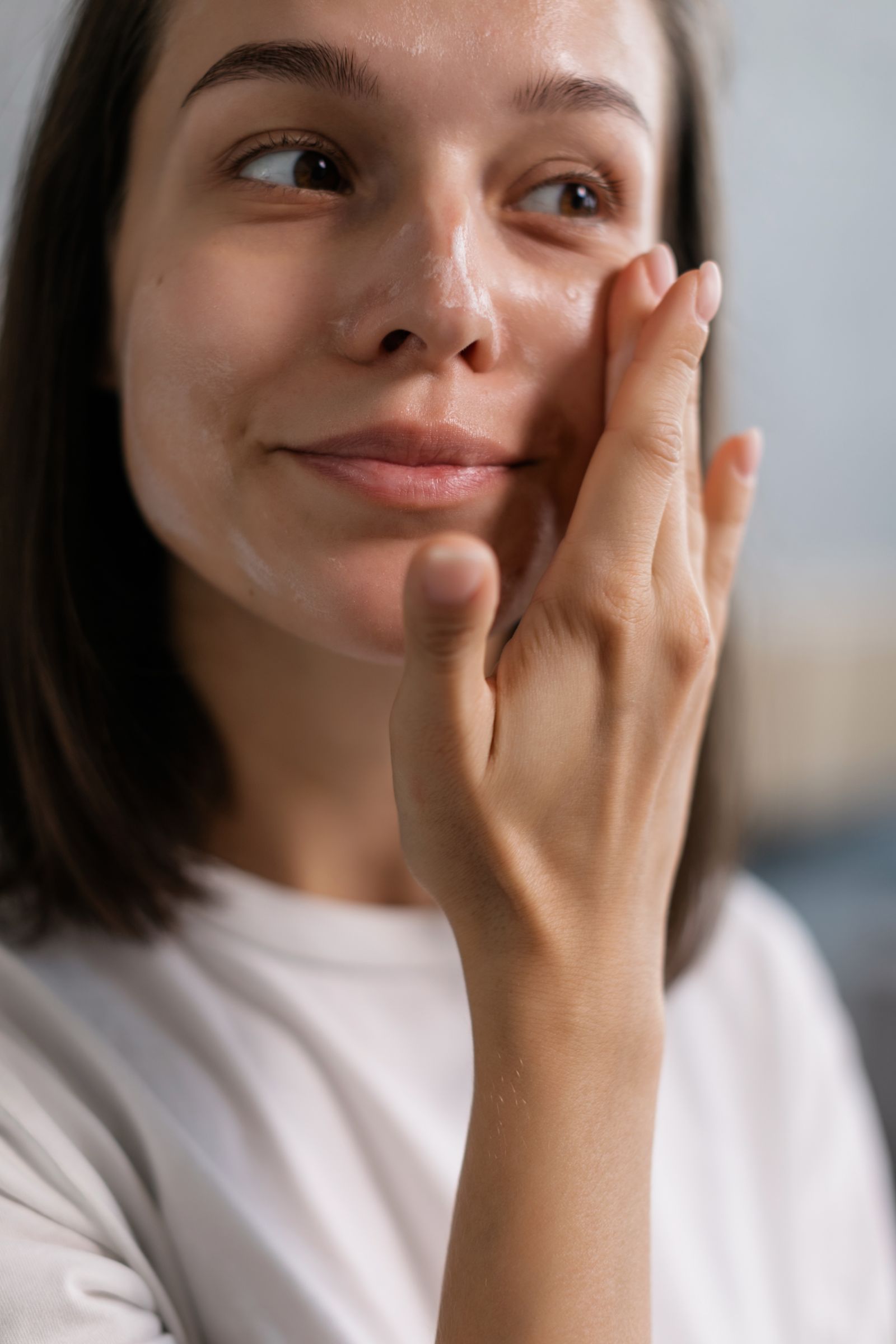 Young adult woman applying facial cream for a fresh dewy skin finish