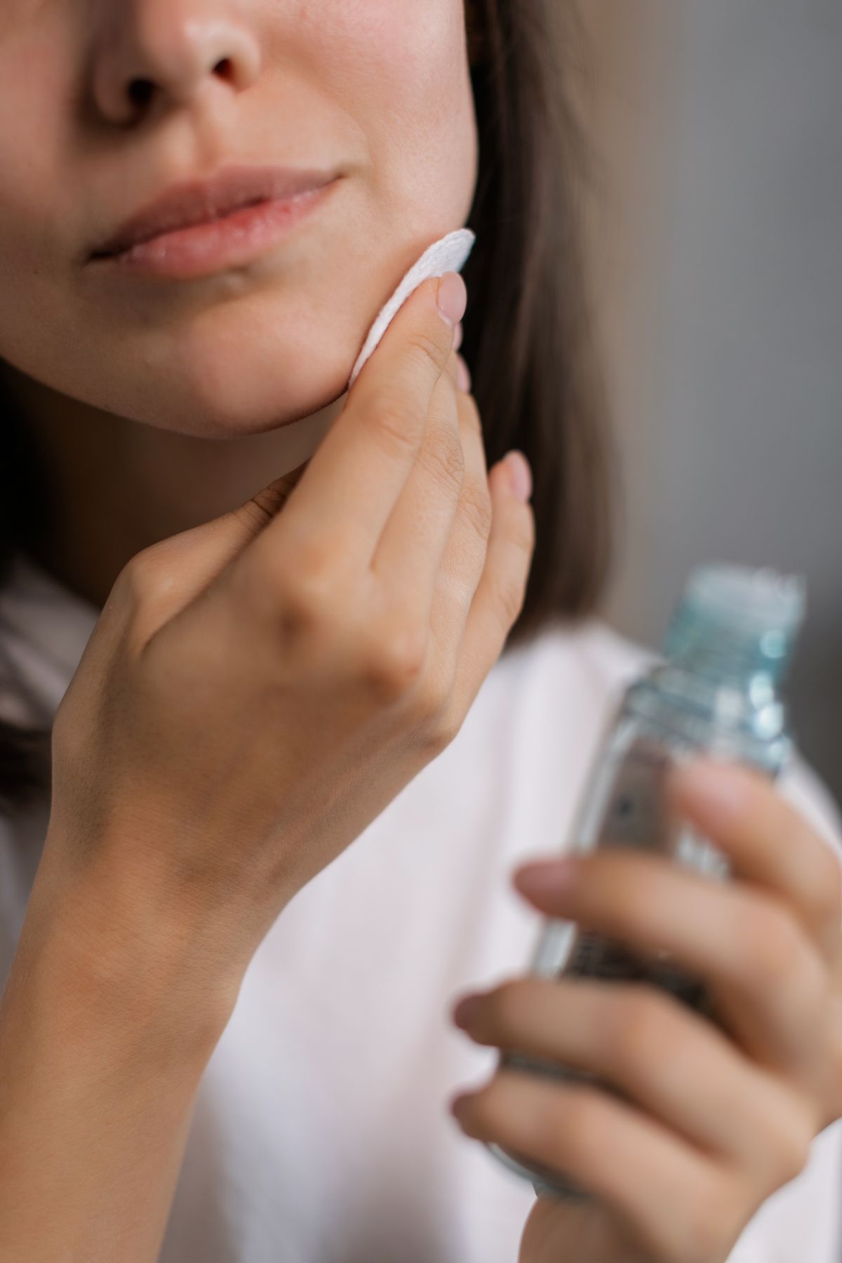 Mulher aplicando produto de skincare com disco de algodão