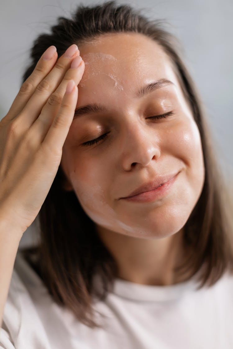 A Young Woman Applying Cream On Face