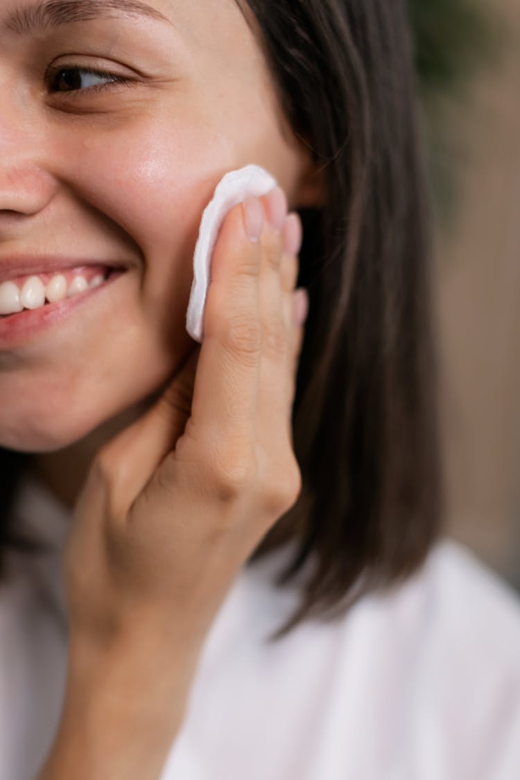 A Woman Cleaning Her Face With A Cotton