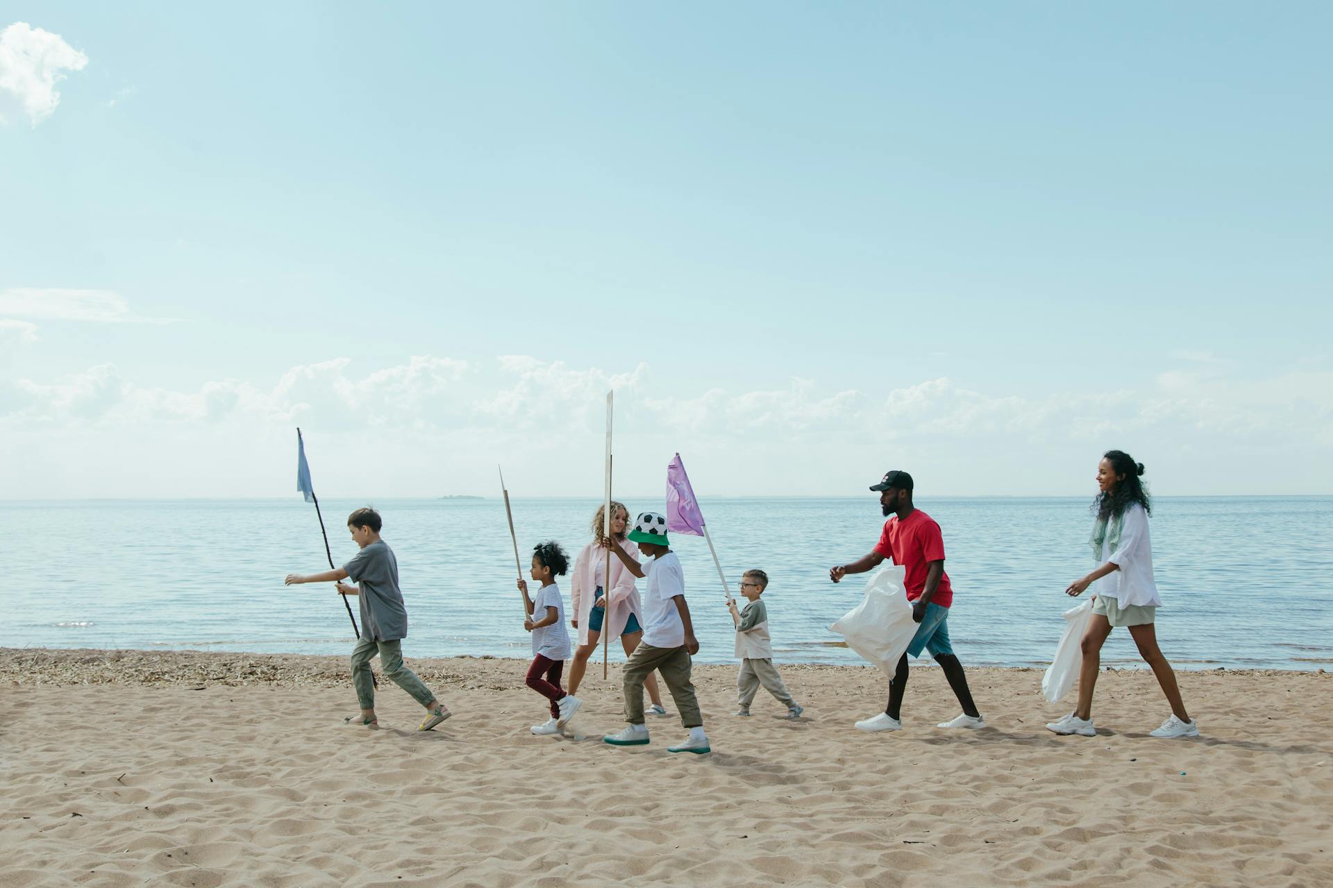 A diverse group of people and children cleaning up a beach together, promoting environmental conservation.