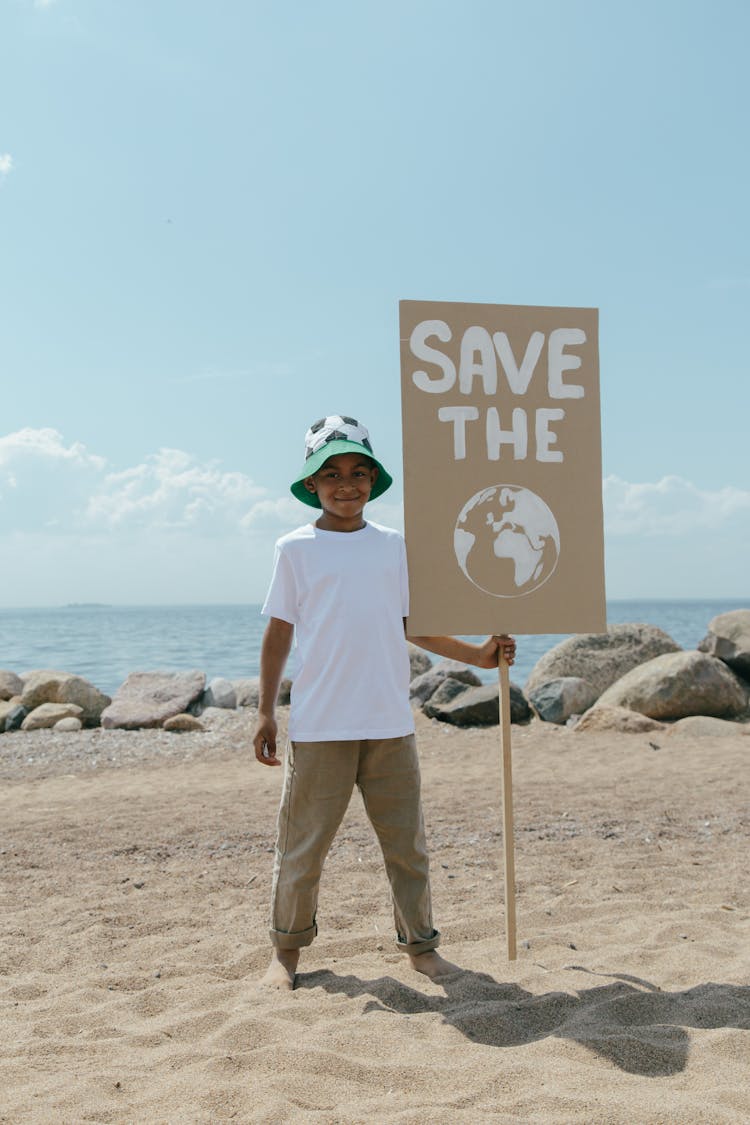 A Boy Holding A Sign On A Beach