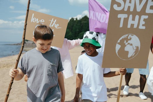 Young children holding signs advocating for environmental awareness at a beach gathering.