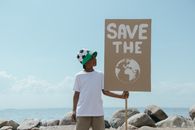Man in White T-shirt Standing on Rock Near Sea