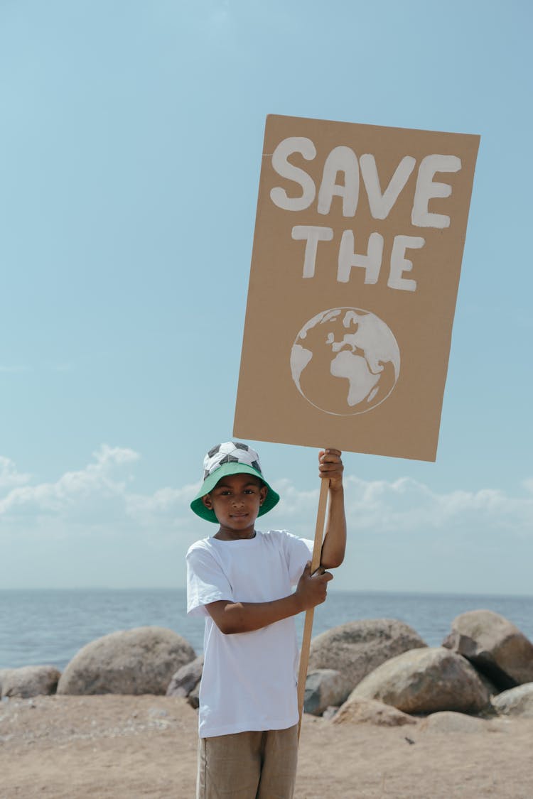 A Young Boy In A Bucket Hat Holding A Picket Sign